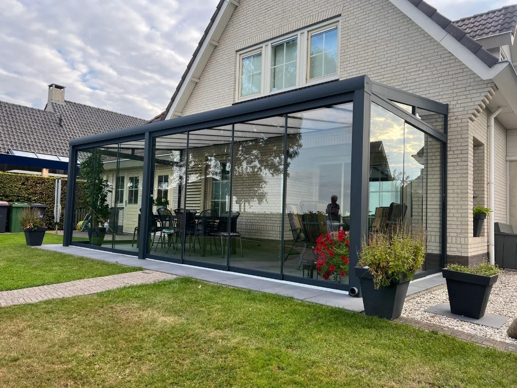 Wintergarten nach Maß aus Aluminium mit Glas-Schiebewänden an einem Einfamilienhaus – lichte Erweiterung mit Blick in den Garten