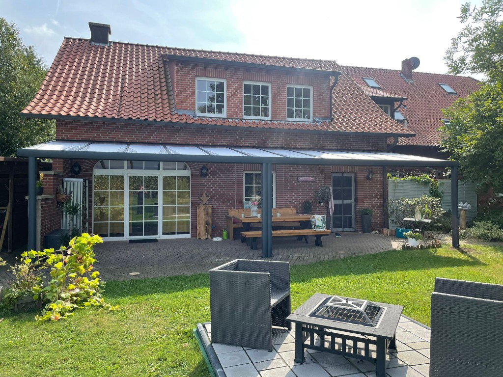 Referenz Bodensee: Breite Aluminium-Terrassenüberdachung mit Glas-Eindeckung an einem Klinker-Bungalow