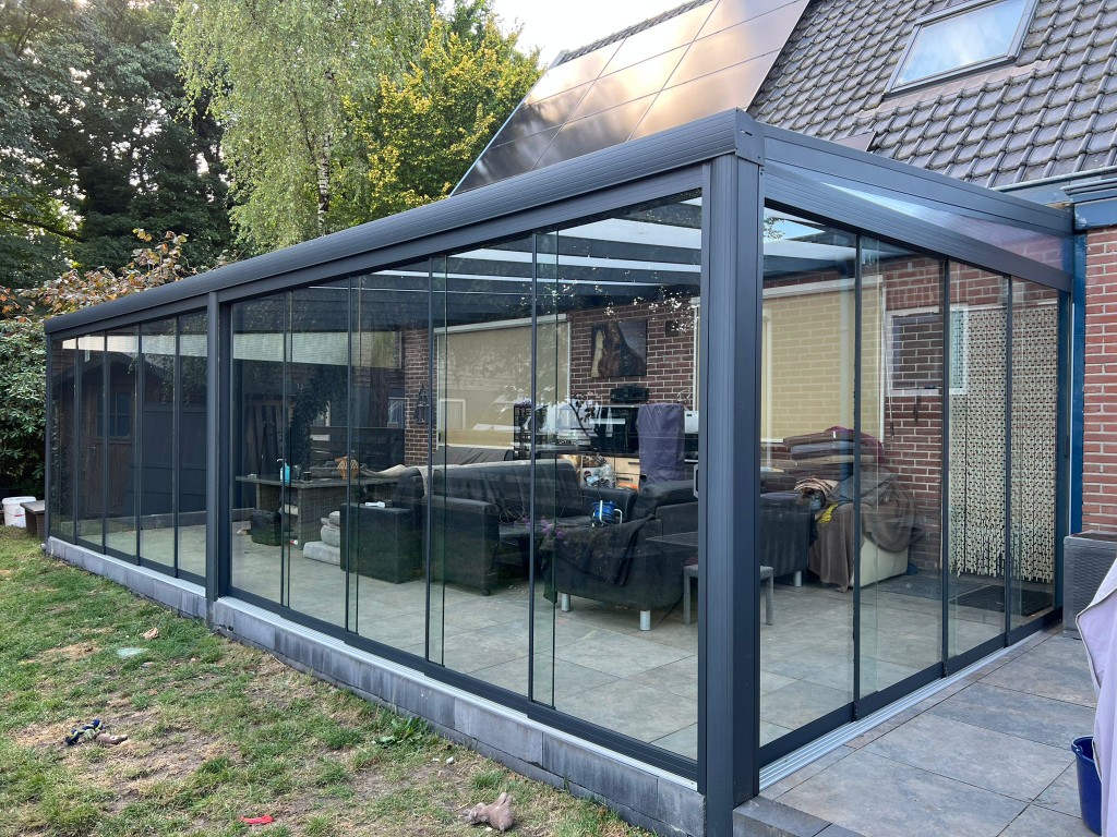 Referenz Mittelfranken: Anthrazitfarbene Aluminium-Terrassenüberdachung mit Glasschiebewänden, montiert an einem Einfamilienhaus